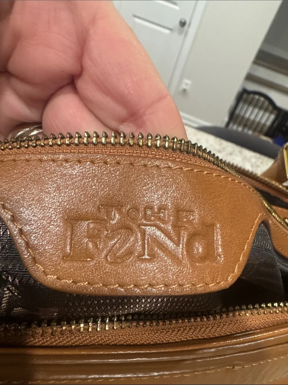 The Find Classic Tan Leather Weekender Travel Bag with Gold Hardware Buckle.